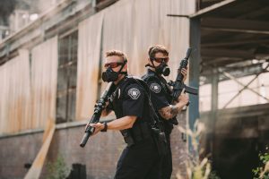 Two officers wearing gas masks and holding AR 15 rifles